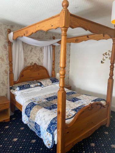 a bedroom with a wooden bed with a wooden frame at Craighlaw Arms Boutique B&B in Kirkcowan