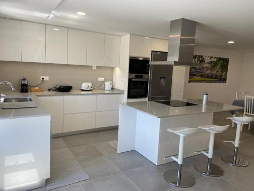 a kitchen with white cabinets and a counter with stools at Casa da Gândara in Ponte de Lima