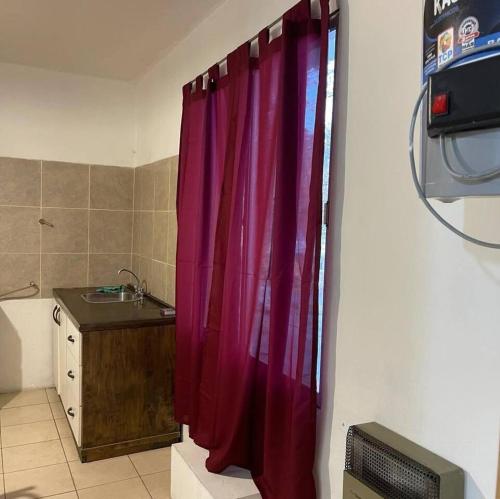 uma casa de banho com uma cortina de chuveiro vermelha e um lavatório. em Deptos San Luis em San Rafael