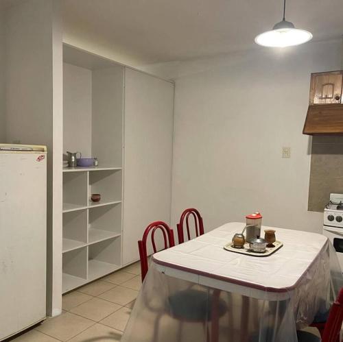 uma cozinha com uma mesa com cadeiras vermelhas e uma toalha de mesa branca em Deptos San Luis em San Rafael