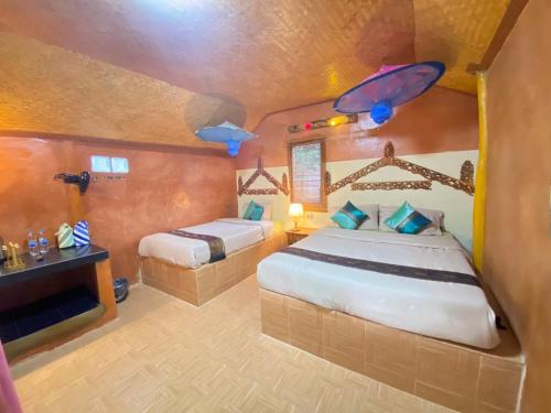 una camera con due letti in una stanza con un pesce sul soffitto di Lung Soi Nguen Homstay Pang Oung a Pang Ung