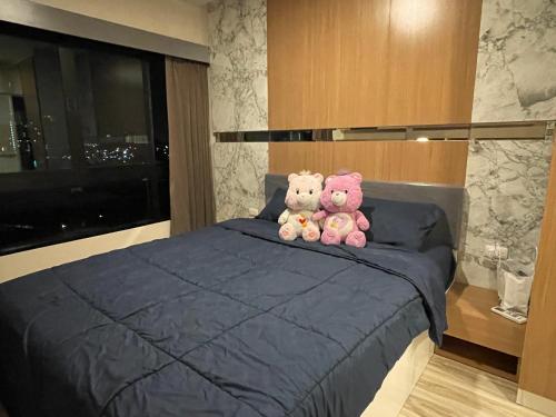 2 ours en peluche assis au-dessus d'un lit dans l'établissement Seaview condo in Siracha (Free onzen), à Si Racha