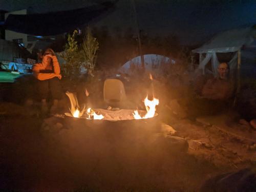 a group of people sitting around a fire at night at guest house אשראם בכרמל - אכסניה in Dāliyat el Karmil