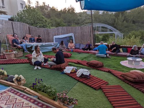 a group of people sitting on the grass at guest house אשראם בכרמל - אכסניה in Dāliyat el Karmil