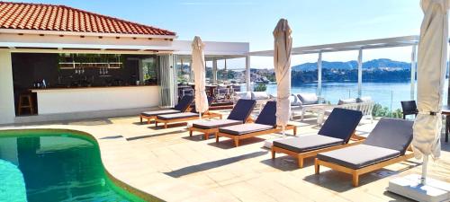a patio with chairs and a pool and a house at VILLA ALEXIS in Megali Ammos