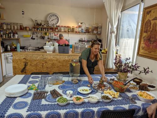 a woman standing at a table preparing food at guest house אשראם בכרמל - אכסניה in Dāliyat el Karmil