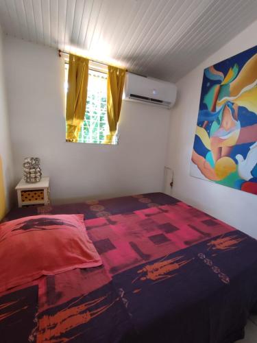 a bedroom with a bed and a painting on the wall at flech kann in Fort-de-France