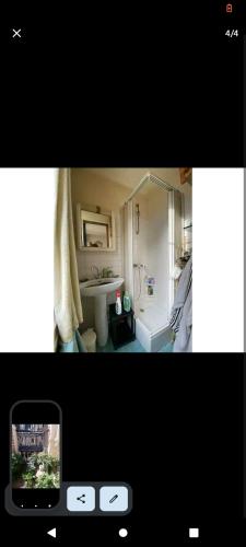een badkamer met een bad, een wastafel en een mobiele telefoon bij chez nayati in Trouville-sur-Mer