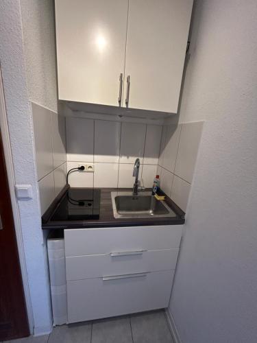 małą kuchnię ze zlewem i białymi szafkami w obiekcie Apartment in Karlsruhe w mieście Karlsruhe