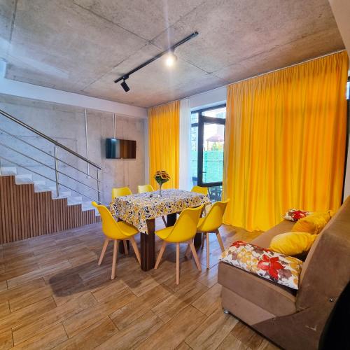 a dining room with a table and yellow chairs at Gina Apartments in Shekvetili