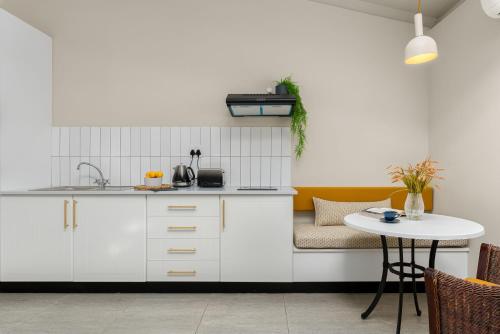 a kitchen with white cabinets and a table at Neighbourgood Franschhoek in Franschhoek