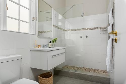 een witte badkamer met een douche en een wastafel bij Neighbourgood Franschhoek in Franschhoek