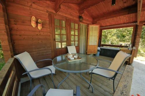 a screened in porch with a glass table and chairs at Domaine La Faix, Gite la Forestière in Saint-Plaisir