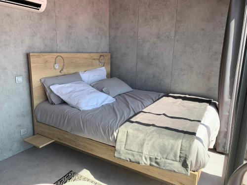 ein Bett mit einem Holzrahmen und Kissen darauf in der Unterkunft Cabane MAIA Aigues Mortes in Aigues-Mortes