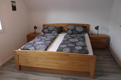 Schlafzimmer mit einem Holzbett mit schwarzen und weißen Kissen in der Unterkunft Ferienhaus Rauhfelsen in Baiersbronn