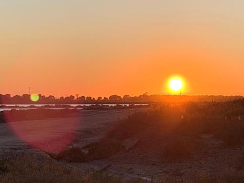 einen Sonnenuntergang über einem Strand mit Sonnenuntergang in der Unterkunft Cabane MAIA Aigues Mortes in Aigues-Mortes
