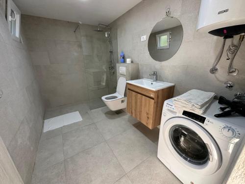 een badkamer met een wasmachine en een toilet bij Sunny village, house with pool in Podgorica