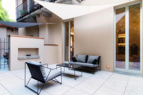 a patio with a couch and a table and chairs at Suites Lorodellago Como - The House Of Travelers in Como