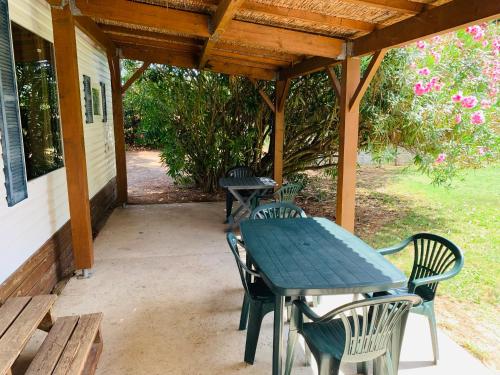 - une table de pique-nique et des chaises sur la terrasse dans l'établissement Mobil Home + dépendance dans jolie parc privé, à Sérignan