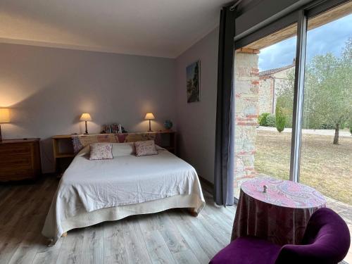 une chambre avec un lit et une grande fenêtre dans l'établissement Gite Le Mas De Marie, à Lavaur