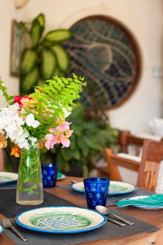 a wooden table with plates and a vase of flowers at Maweni House - Beachfront, Pool, AC & Cook in Kilifi
