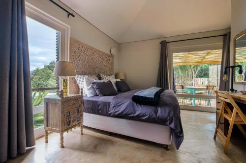 1 dormitorio con cama y ventana grande en Treebia Self-catering - Loadshedding Free en Plettenberg Bay