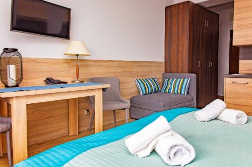コウォブジェクにあるApartamenty PROMENADA-Arkaのベッド、テレビ、椅子が備わるホテルルームです。