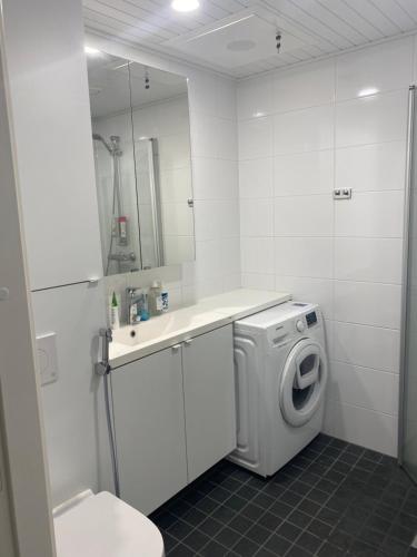 a white bathroom with a washing machine and a sink at Apartment Vito in Vantaa