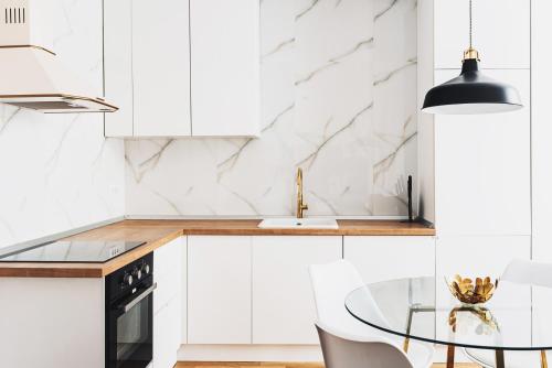 a kitchen with white cabinets and a glass table at VOYA Apartments - a luxury oasis in the old town in Braşov