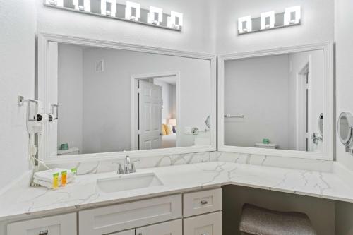 a white bathroom with a sink and two mirrors at The Epic Dublin Vista Cay Orlando in Orlando