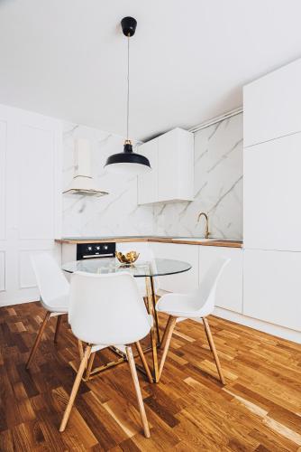 a kitchen with a glass table and white chairs at VOYA Apartments - a luxury oasis in the old town in Braşov