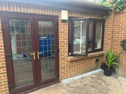 a brick house with glass doors and a potted plant at Cosy Studio Flat in Bexleyheath