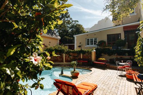 um quintal com piscina e cadeiras e uma casa em Carmichael House Boutique Hotel na Cidade do Cabo