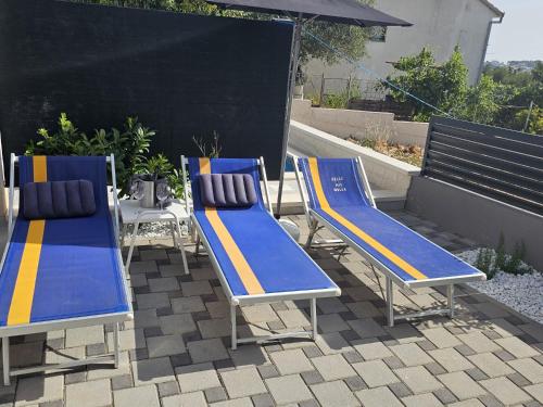 3 chaises bleues et jaunes et une table sur une terrasse dans l'établissement Villa BOTIĆ, à Trogir