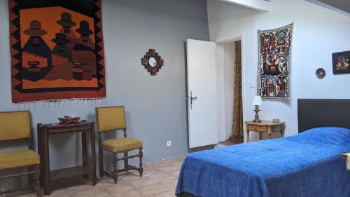 une chambre avec un lit bleu et deux chaises dans l'établissement Les gites d'intervalles, à Entrevaux