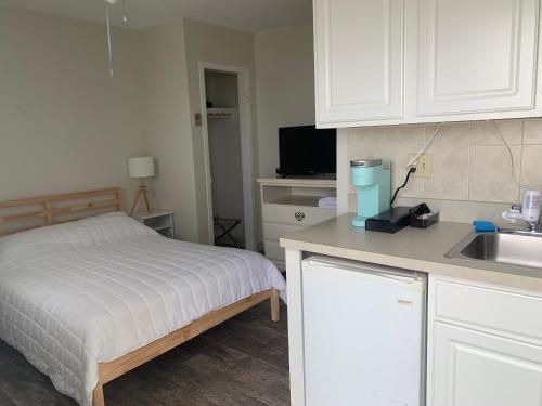 a small kitchen with a bed and a sink at Southold Beach Motel in Southold