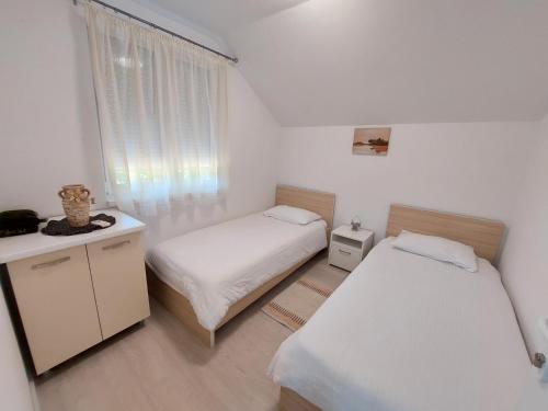 コニツにあるKuća-Villa pored rijeke i jezera Čelebići Konjicのベッド2台と窓が備わる小さな客室です。