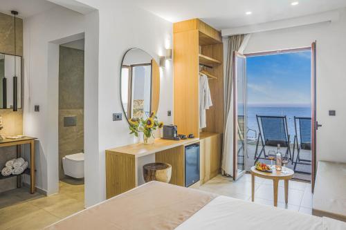 a bedroom with a bathroom with a view of the ocean at Panorama Village Hotel in Agia Pelagia