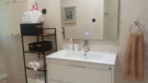 ein Badezimmer mit einem Waschbecken, einem Spiegel und Handtüchern in der Unterkunft Ohana, Apartamento-CENTRICO-WIFI-ASCENSOR- PARKING PRIVADO GRATIS-SIN CUESTAS in Bermeo