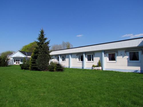 a white building with a green lawn in front of it at Fleninge Classic Motel in Fleninge