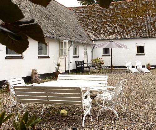 a white house with a table and chairs and an umbrella at Hvidegaard Møn in Stege