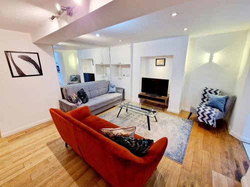 a living room with a red couch and a tv at Beautiful Hyde Park Flat by Lancaster Gate Station with Private Back Patio in London