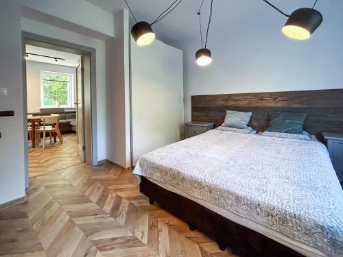 a bedroom with a bed with a wooden headboard and lights at Apartament Centrum B in Wejherowo