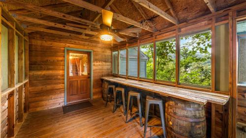 a bar in a log cabin with a ceiling fan and windows at Whiskey Ridge Lodge, A Restored 1940s Gem, 2 Mins from Downtown, Breathtaking City Views, Custom Game Room, and Spacious Elegance in Gatlinburg