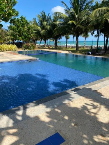 une grande piscine avec des palmiers et l'océan dans l'établissement Sandy Shores, à Trincomalee