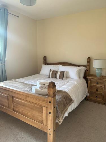 a bedroom with a wooden bed with white sheets and pillows at Stunning cozy three bedroom house near ARI in Aberdeen
