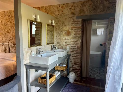 a bathroom with two sinks and a bed and a tub at Le Mas De Marie in Lavaur