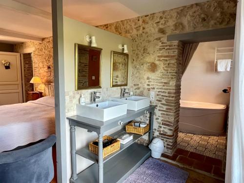 ein Badezimmer mit zwei Waschbecken, einem Bett und einer Badewanne in der Unterkunft Le Mas De Marie in Lavaur