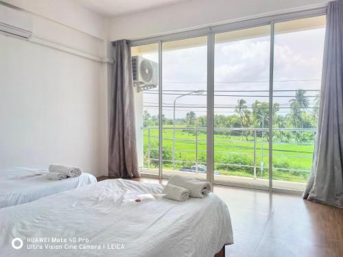 a bedroom with two beds and a large window at YYK Townhouse in Ban Khlong Krang