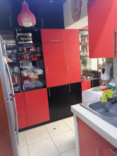 een keuken met rode kasten en een zwarte koelkast bij Residencial Las Torres de Salaverry in Chiclayo